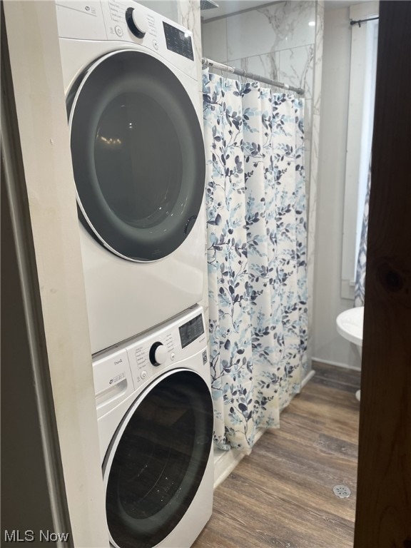 clothes washing area with dark hardwood / wood-style floors and stacked washing maching and dryer