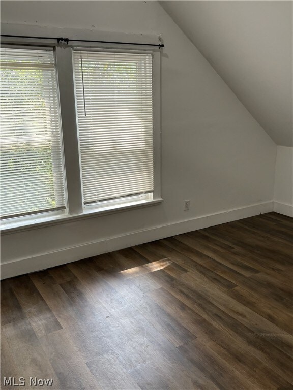 bonus room featuring plenty of natural light, dark wood-type flooring, and vaulted ceiling