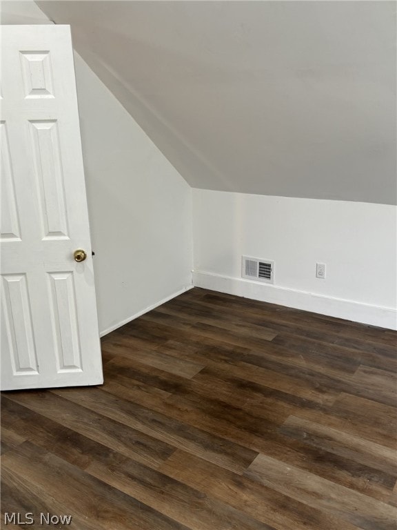 additional living space with vaulted ceiling and dark hardwood / wood-style flooring