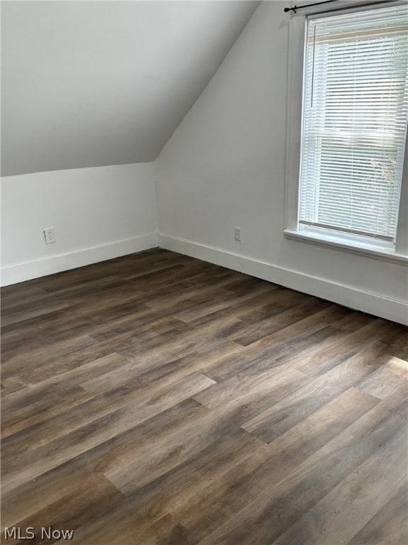 additional living space with dark hardwood / wood-style flooring and vaulted ceiling