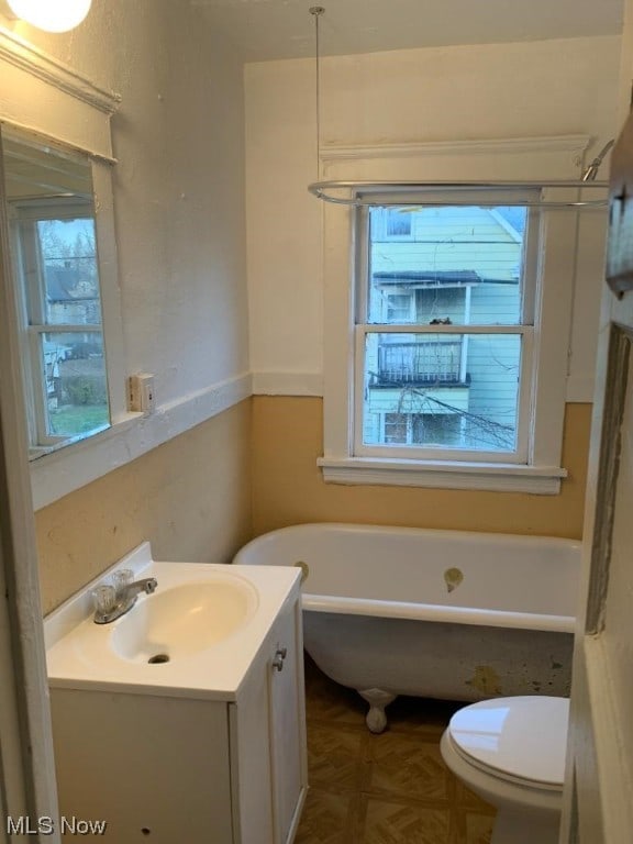 bathroom featuring vanity, parquet floors, a bath to relax in, and toilet