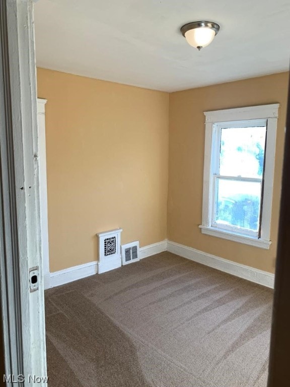 spare room featuring dark colored carpet