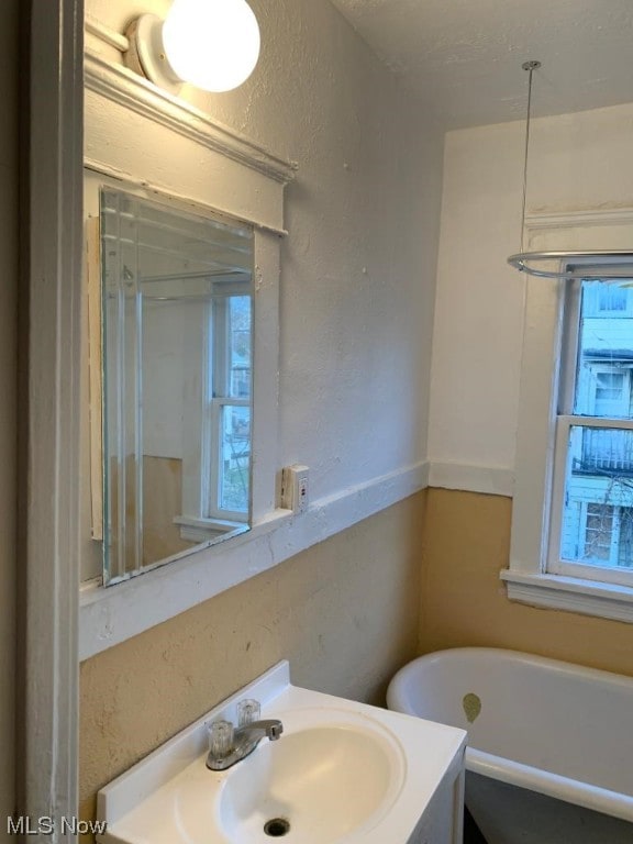 bathroom featuring a bath to relax in and oversized vanity