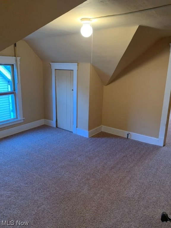 bonus room with light carpet and vaulted ceiling