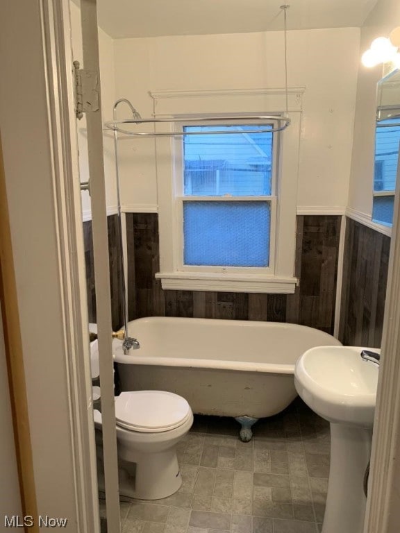 bathroom with tile flooring, a bathing tub, and toilet