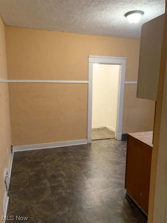 empty room featuring dark tile floors and a textured ceiling