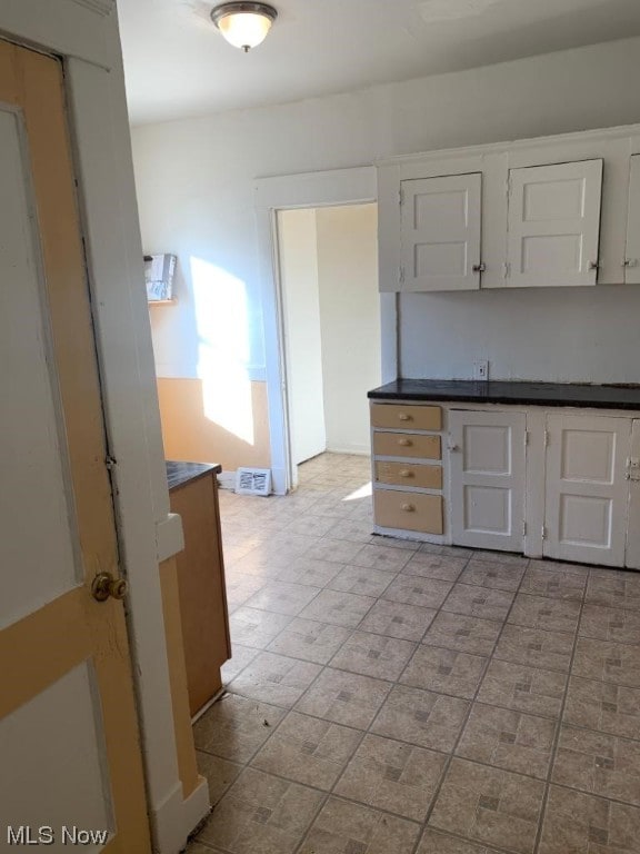 kitchen with light tile flooring and white cabinets