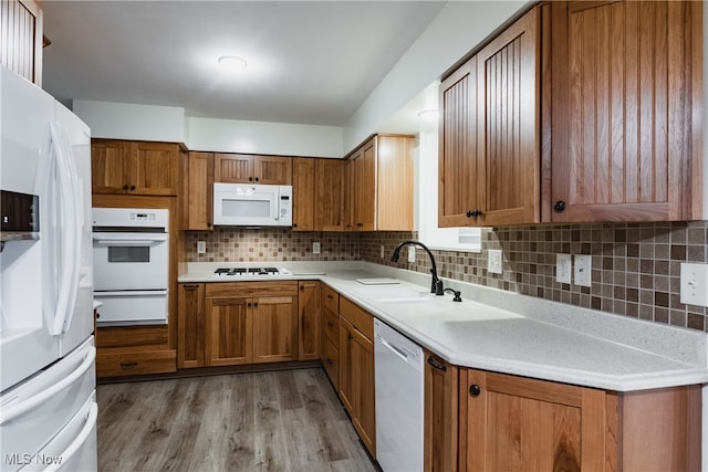 kitchen featuring light wood-type flooring, sink, white appliances, and decorative backsplash