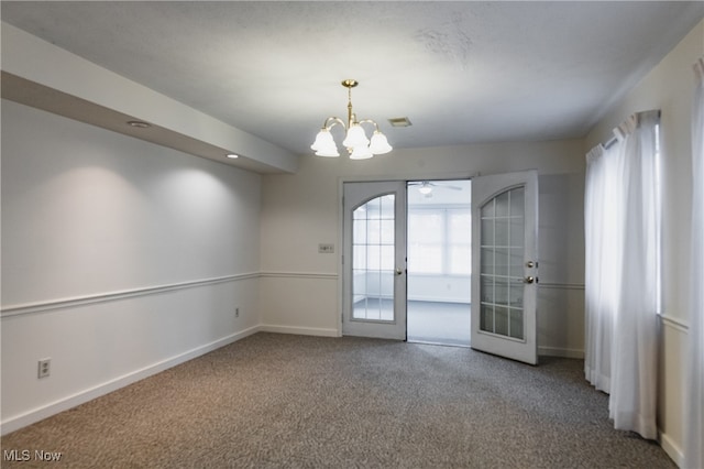 empty room with ceiling fan with notable chandelier, carpet floors, and french doors