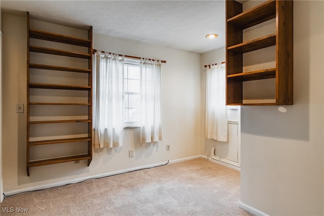 carpeted empty room featuring a textured ceiling