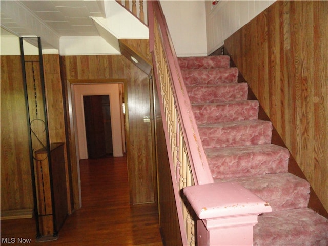 stairs with wooden walls and dark hardwood / wood-style flooring