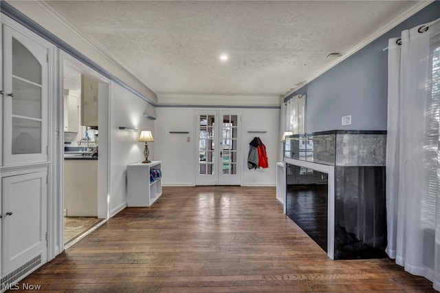 interior space featuring french doors, dark hardwood / wood-style flooring, a textured ceiling, and crown molding