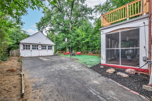 exterior space featuring a balcony, a garage, an outdoor structure, and a sunroom