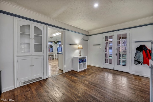 spare room featuring dark hardwood / wood-style flooring, ornamental molding, french doors, and a textured ceiling