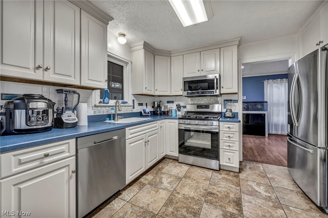 kitchen featuring sink, white cabinetry, stainless steel appliances, tasteful backsplash, and a textured ceiling