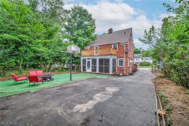 back of house featuring a lawn, a sunroom, and a balcony