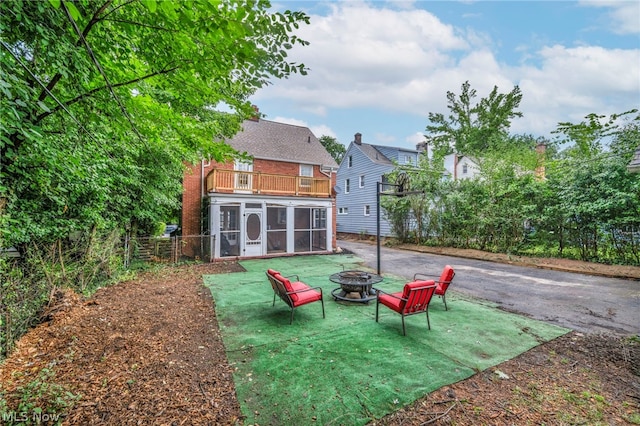 view of yard featuring a balcony, a sunroom, and an outdoor fire pit