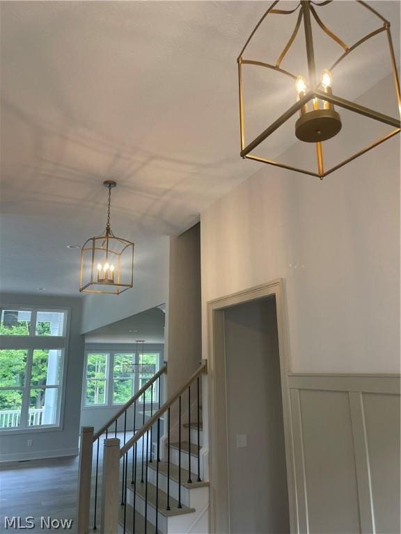 staircase featuring an inviting chandelier and wood-type flooring