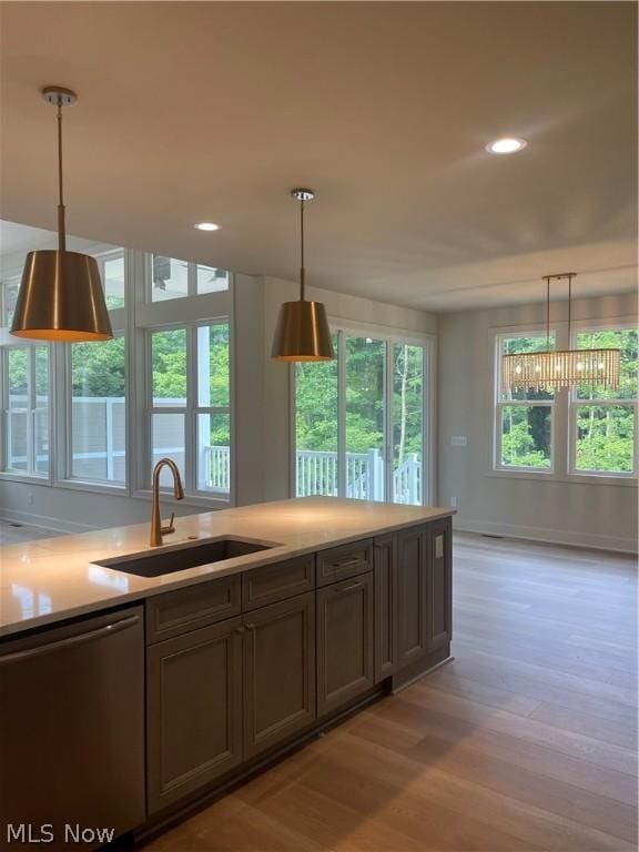 kitchen featuring dishwasher, hanging light fixtures, an inviting chandelier, light wood-type flooring, and sink