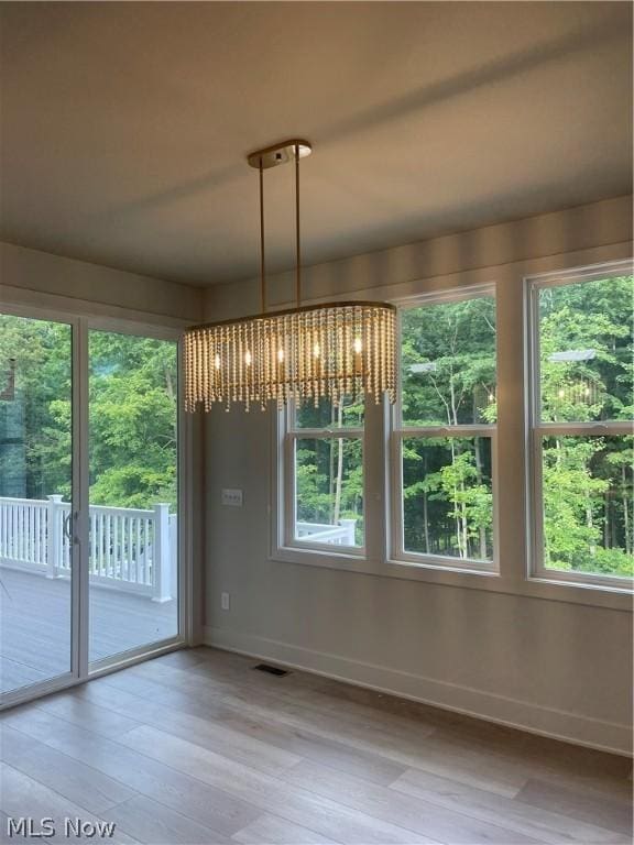 unfurnished dining area featuring a chandelier and hardwood / wood-style flooring