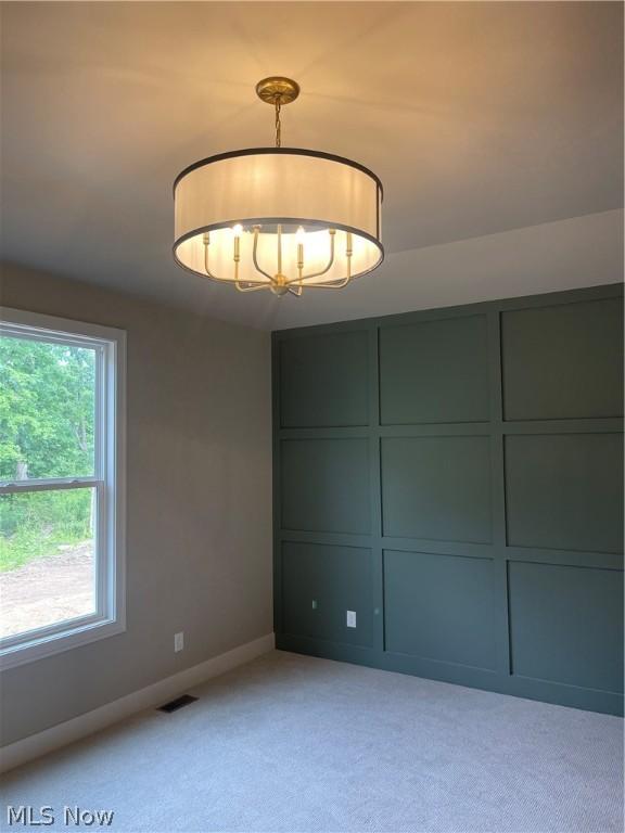 carpeted spare room with a notable chandelier