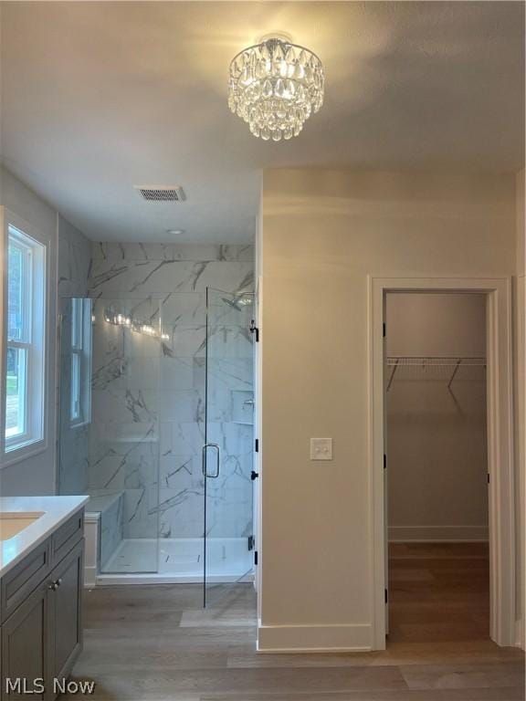 bathroom with a shower with door, vanity, an inviting chandelier, and hardwood / wood-style flooring