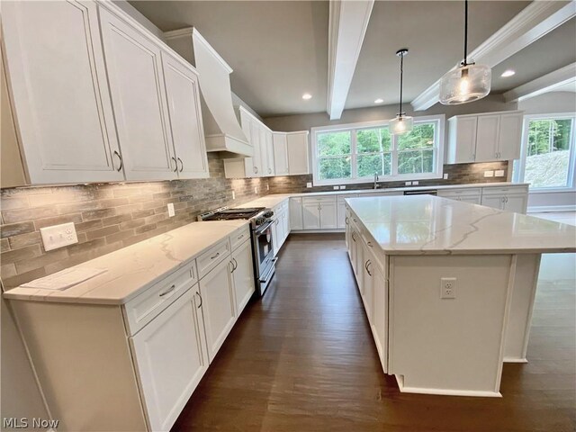 kitchen featuring stainless steel range, pendant lighting, white cabinetry, and a kitchen island