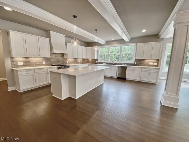 kitchen with white cabinets, premium range hood, appliances with stainless steel finishes, and beamed ceiling