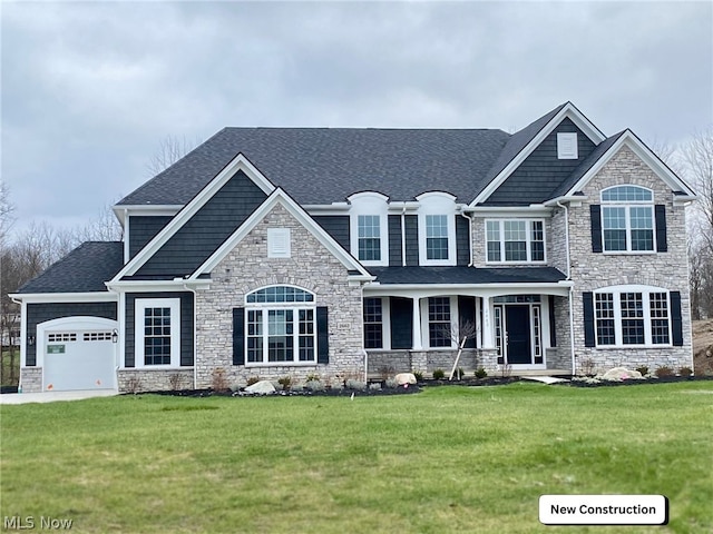 craftsman-style home featuring a garage, driveway, a shingled roof, and a front yard