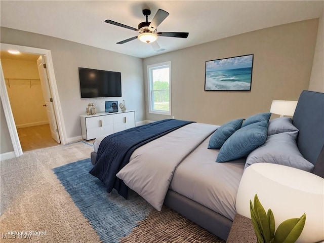 carpeted bedroom with a walk in closet, ceiling fan, and a closet