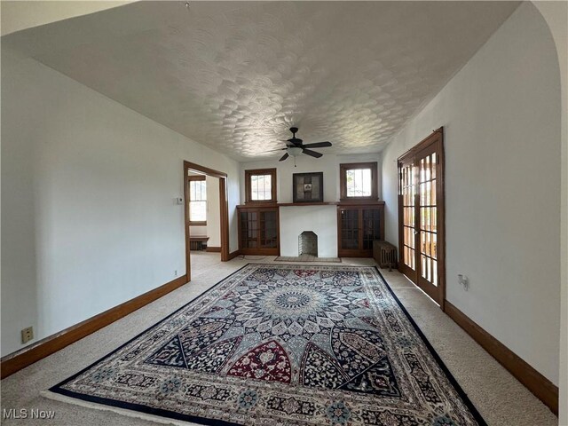 living room with a textured ceiling, radiator heating unit, and ceiling fan