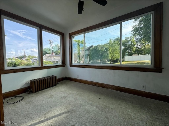 unfurnished room featuring carpet floors, radiator heating unit, and ceiling fan