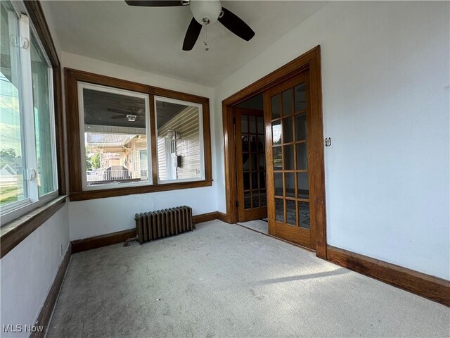 spare room featuring ceiling fan, radiator, and carpet floors