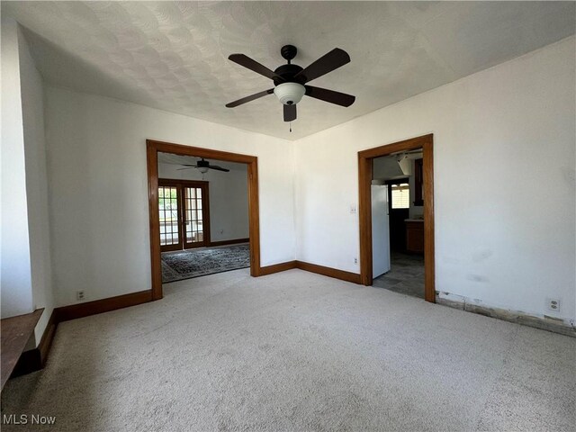 empty room featuring french doors, light carpet, and a textured ceiling