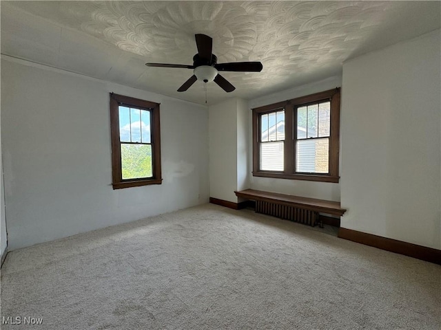 empty room with a healthy amount of sunlight, radiator, and light colored carpet