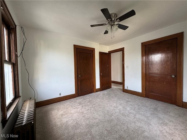 unfurnished bedroom featuring ceiling fan, carpet flooring, radiator, and a textured ceiling