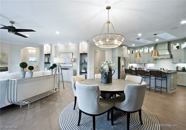 dining space featuring sink, ceiling fan with notable chandelier, hardwood / wood-style flooring, and crown molding