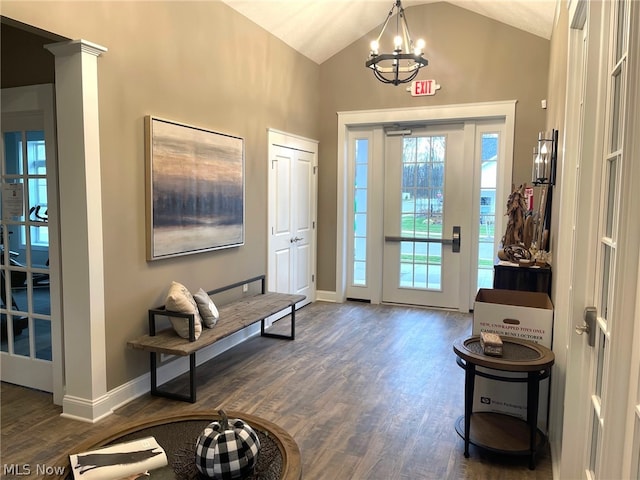 foyer featuring dark hardwood / wood-style floors, lofted ceiling, ornate columns, and an inviting chandelier