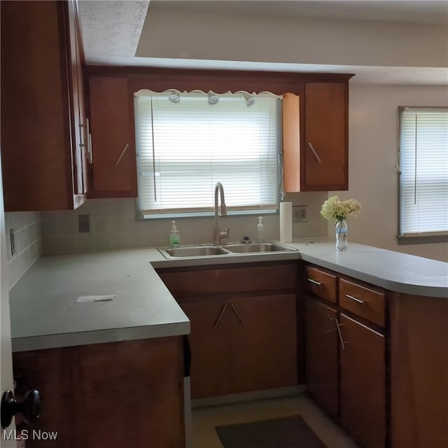 kitchen featuring kitchen peninsula, tasteful backsplash, sink, and plenty of natural light