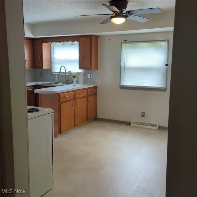 kitchen featuring stove, sink, backsplash, light tile patterned flooring, and ceiling fan