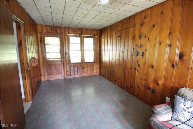 unfurnished room featuring wood walls and dark tile patterned floors