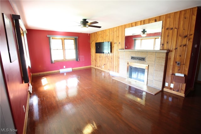 unfurnished living room with hardwood / wood-style floors, ceiling fan, and wooden walls