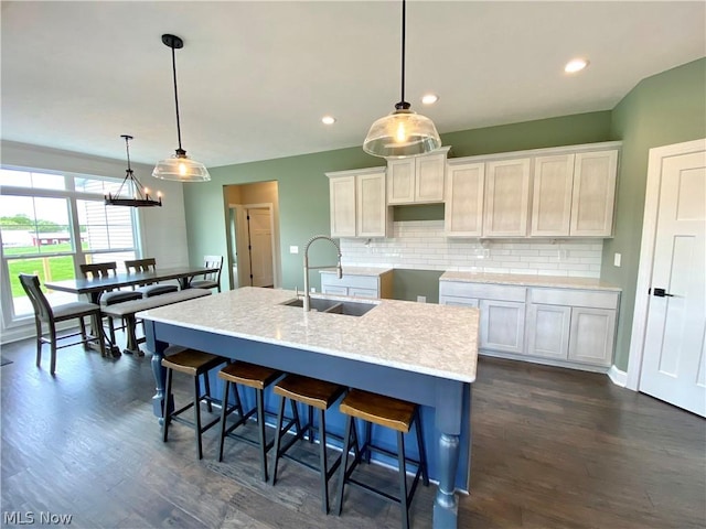 kitchen with dark wood-type flooring, a sink, backsplash, and a kitchen breakfast bar