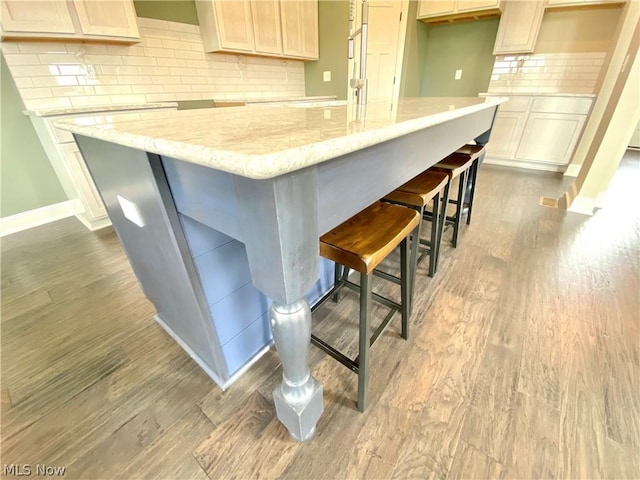 kitchen featuring light stone countertops, dark wood-style floors, baseboards, and backsplash