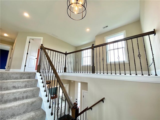 stairway with an inviting chandelier, a high ceiling, visible vents, and recessed lighting