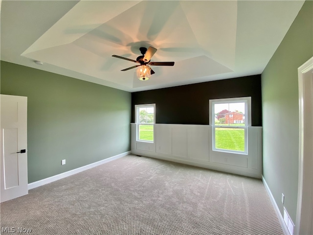 carpeted empty room with ceiling fan and a tray ceiling