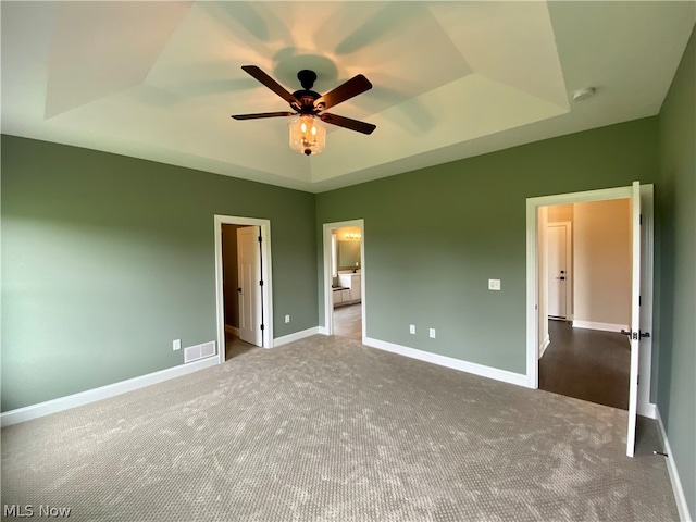 unfurnished bedroom with a tray ceiling, carpet floors, and ceiling fan