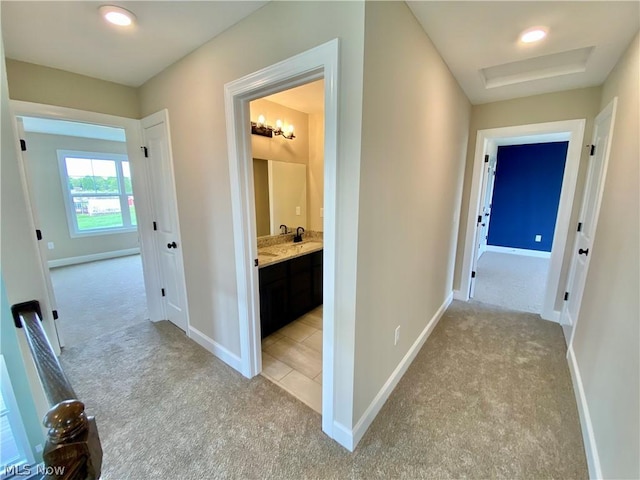 hall with baseboards and light colored carpet