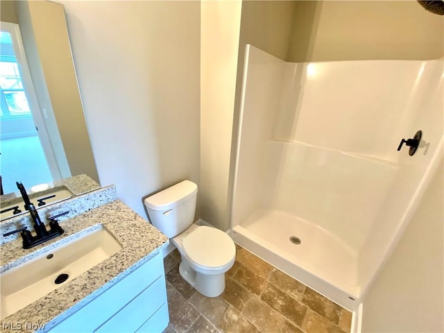 bathroom featuring toilet, a shower stall, stone finish floor, and vanity