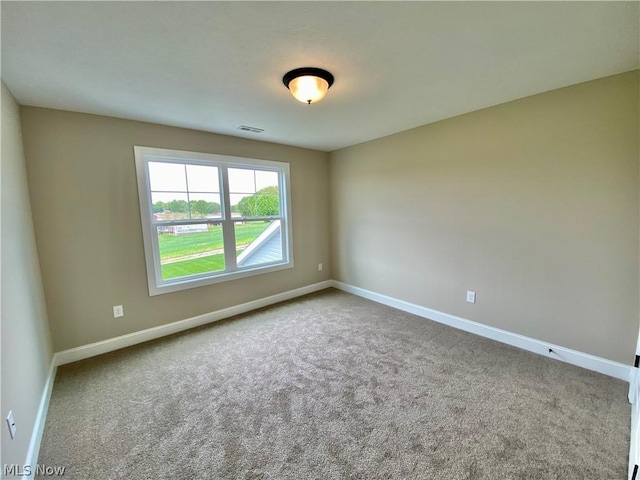 empty room featuring carpet floors, visible vents, and baseboards